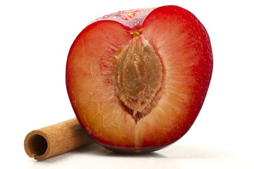 half wet plum with a cinnamon stick on white background