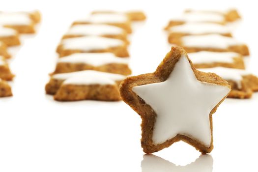 one star shaped cinnamon biscuit in front of many on white background