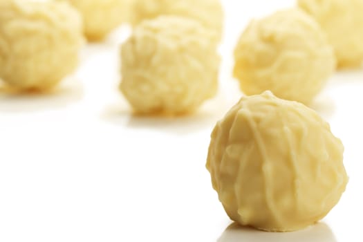 yellow truffle praline in front of many on white background