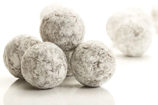 some sugar powder covered truffle pralines on white background
