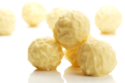 some yellow truffle pralines in front of others on white background