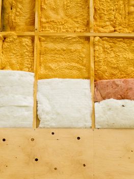 Different types of building insulation: polyurethane spray foam and fiberglas mats.