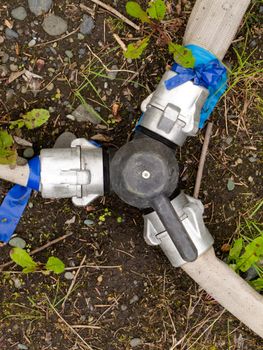 3-way connector valve with fire hoses attached to fittings on forest floor.