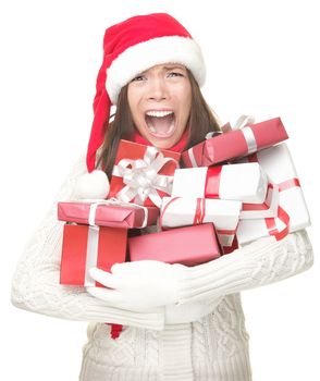 Christmas holidays shopping woman stress. Shopper holding christmas gifts stressed, frustrated and screaming angry. Funny image of Asian / caucasian woman in santa hat and arms full of gifts. Isolated on white background.