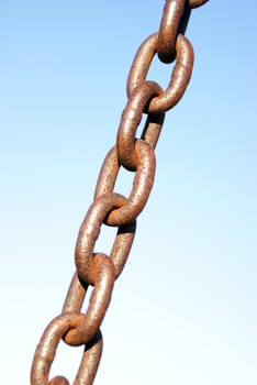 A rusted link of chain over a blue background.