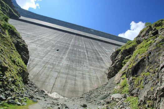 View of Grande Dixence dam from down next to big rocks by sunny weather, Switzerland