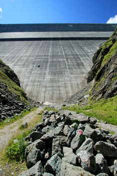 View of Grande Dixence dam from down next to big rocks by sunny weather, Switzerland