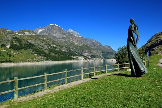 Sculpture Lady of the lake looking at the Chevril lake and dam. On the site, it is possible to read : "Statue memorial by sculptor Livio Benedetti celebrating both the memory of former Tignes and looks to the future.". The dam was inaugurated in 1953 and destroyed the old village of Tignes.