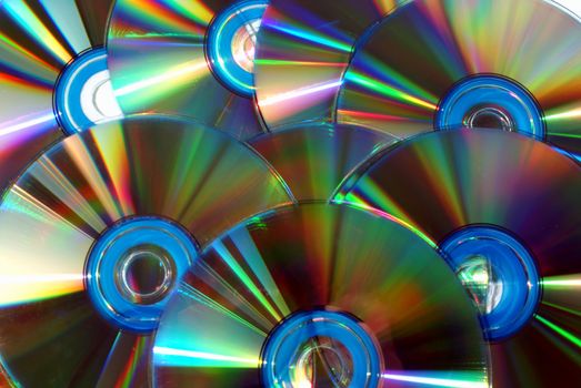 A rainbow reflection on a group of CD or DVD disks.