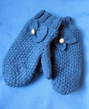 Blue wool mittens with a decorative bow on a blue background.                              