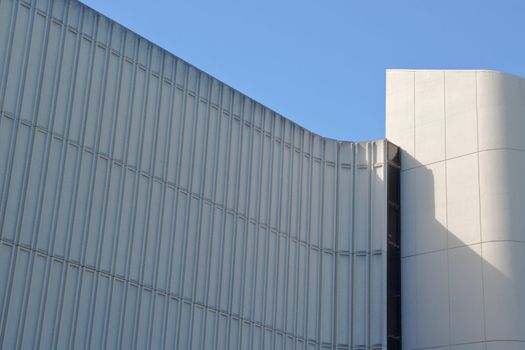 Curves lines and tower of building with small glass window against blue sky