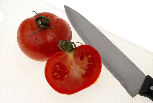 Cutting white plastic board with a knife and tomato isolated on a white background.