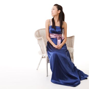 Elegant lady of Asian sit and watch in formal dress on white.