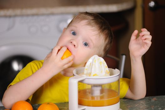 The child in a yellow vest to wring out juice  from an orange