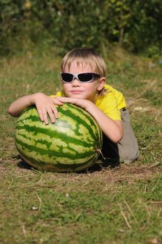 The child with a watermelon on a lawn in a wood