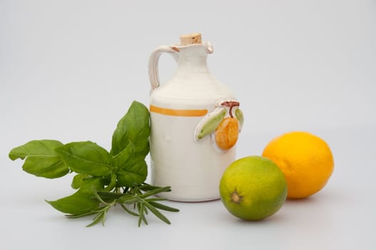 A lemon olive oil jug and lemon, lime and herbs. isolated