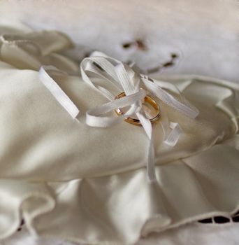 Wedding gold ring placed on a white heart-shaped pillow