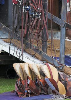 Collection of saddles and other tack at a polo match.