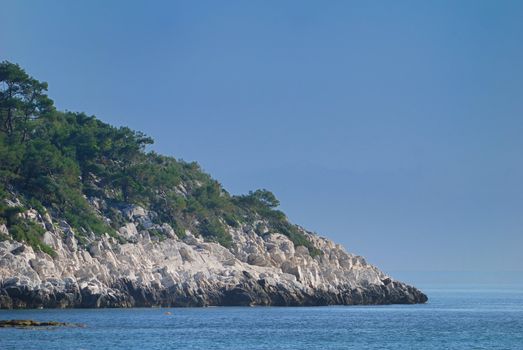 steep cape of rock island on a clear blue day
