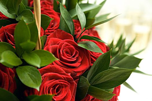 Fine wedding bouquet from set of red roses and green leaves close up

