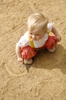 little girl sitting on a sand on a playground
