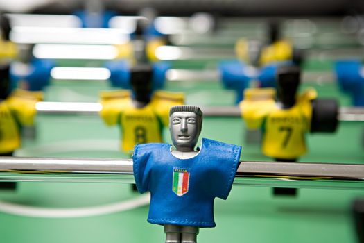 Image of desktop football with plastic players in the dark blue and yellow form close up on a green background
