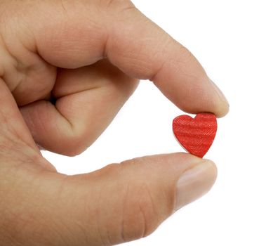 A hand shows a small wood and painted red heart between it's two fingers in front of a white background.