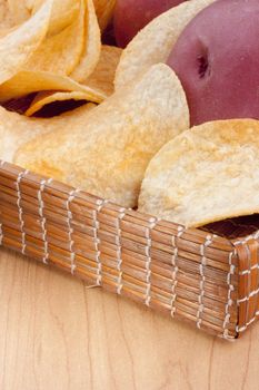 Potato chips with a potato on a wooden tray.