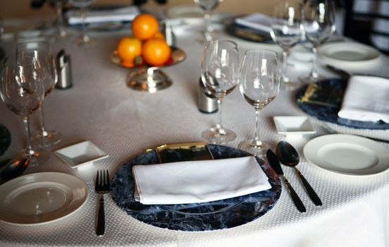 Decorative table place setting with silver cutlery glasses and oranges