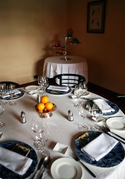 Decorative table place setting with silver cutlery glasses and oranges