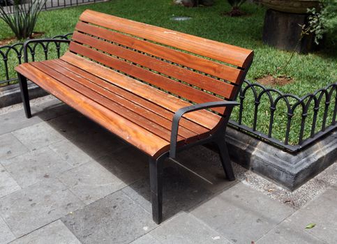 Wooden bench in clean park with green grass