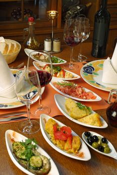 A table setting full of traditional Spanish tapas and wine.
