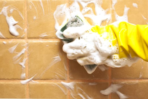 hand in yellow rubber glove holding soapy cleaning sponge 