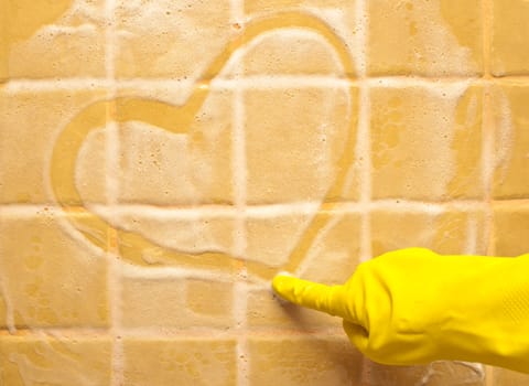 hand in yellow rubber glove draws heart