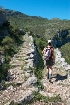 An athletic woman trekking along a mountain trail