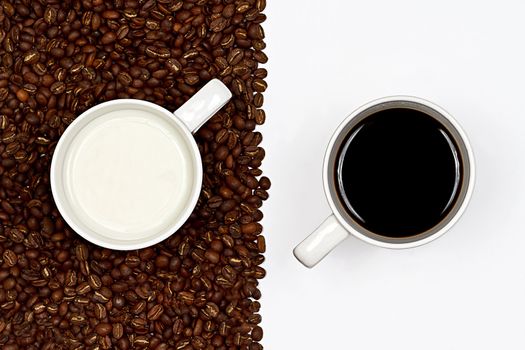 A cup of black coffe on white background and a cup of white milk on a layer of coffee beans