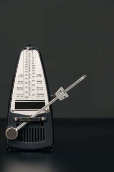 Metronome in motion before a neutral grey background