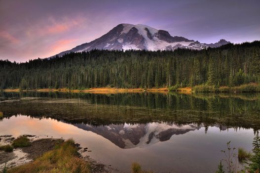 Mount Rainier reflected across the reflection lakes at dusk under a dramatic sky