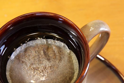 A bag of tea sitting a mug of hot water.