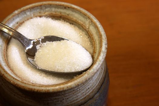 A spoonful of sugar sitting in a bowl of a sugar.