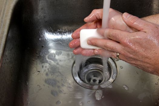 A man washing his hands with soap in a sink.
