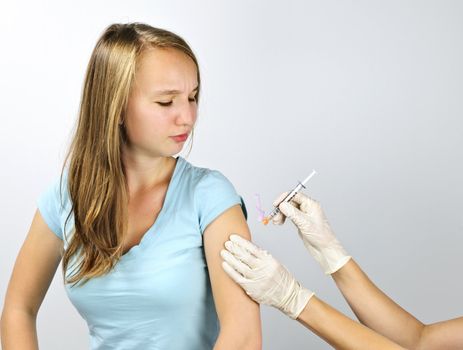 Teenage girl getting flu shot needle vaccination in arm