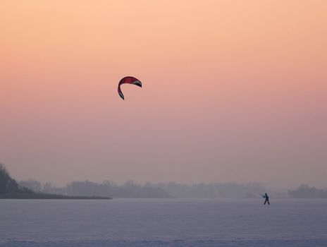 Playing with a kite on a frozen lake at sunset