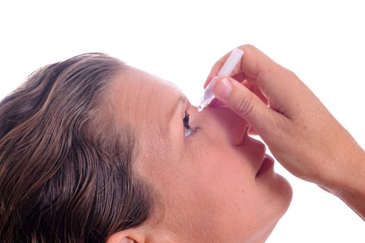 a mature woman applying eyedrops in front of a white background