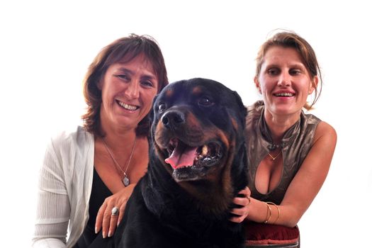 two smiling women and a purebred rottweiler in front of a white background