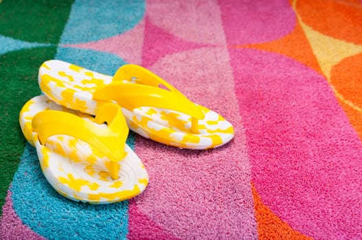 Bright yellow flip-flops on a colorful beach towel