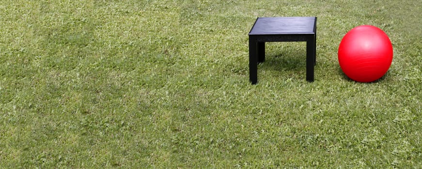 Black table and red ball on the grass