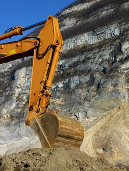 Orange mechanical digger arm next to a mountain