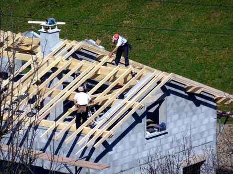 Carpenter building a roof of a house at a construction site