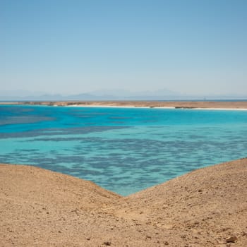 Turquoise waters and gentle waves of a golden sand beach with deep blue sky.